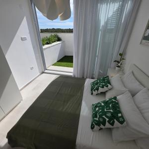 a white bed in a room with a large window at Sunrise & Sunset villa Šimuni by Pag tours in Šimuni
