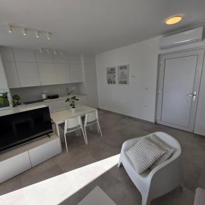 a white living room with a table and a kitchen at Sunrise & Sunset villa Šimuni by Pag tours in Šimuni