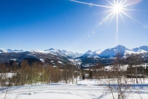 a sun shines over a snow covered mountain range at Fjellro in Stranda +1 photo