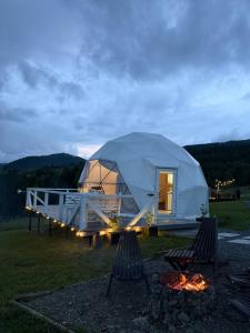 a dome tent with two chairs in front of a fire at Forest glamp in Yasinya