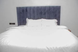 a large white bed with white sheets and pillows at Five Star Meekness Hotel LTD in Oviri