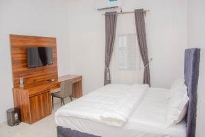 a bedroom with a bed and a desk with a television at Five Star Meekness Hotel LTD in Oviri +6 photos