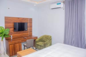 a bedroom with a bed and a chair and a tv at Five Star Meekness Hotel LTD in Oviri