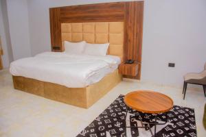 a bedroom with a bed with a wooden headboard and a table at Five Star Meekness Hotel LTD in Oviri