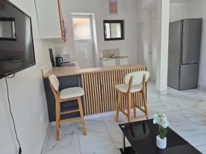 a kitchen with two chairs and a counter with a refrigerator at Maison chaleureuse avec tous confort in Elbeuf