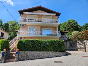 a yellow house with white balconies and a fence at Apartman Ruza 3 in Poljane