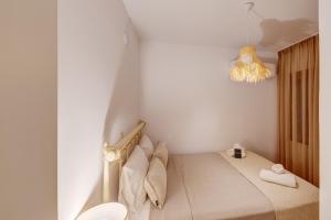a white room with a bed and a chandelier at Villa Marelia - Seafront villa with infinity pool in Megas Gialos - Nites