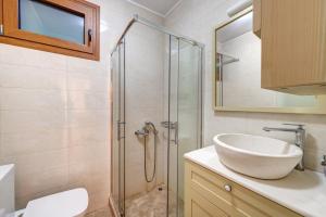 a bathroom with a sink and a glass shower at Villa Marelia - Seafront villa with infinity pool in Megas Gialos - Nites +77 photos