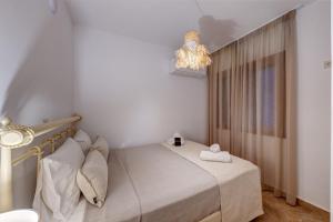 a small bedroom with a bed and a chandelier at Villa Marelia - Seafront villa with infinity pool in Megas Gialos - Nites