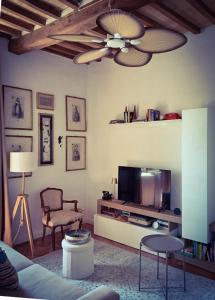 a living room with a television and a ceiling fan at La Casina Tuscan Countryside View in Murlo
