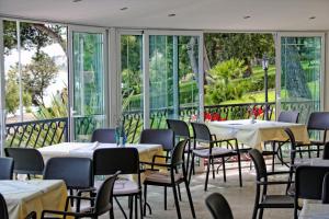 ein Restaurant mit Tischen, Stühlen und Fenstern in der Unterkunft Hotel Val in Trogir