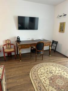 a desk with a chair and a television on a wall at Hotel Traube in Mediaş