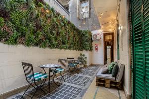 a patio with chairs and tables and a green wall at Casa Lima Sur in Buenos Aires