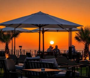 a group of people sitting at tables under an umbrella at Al Hoceima Luxury Residence Amina 3 in Al Hoceïma