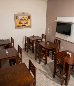 a restaurant with wooden tables and chairs and a flat screen tv at Hotel Natal in Santos