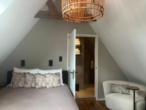 a bedroom with a bed and a chair and a chandelier at Bij ons op de Hoep. in Schagen