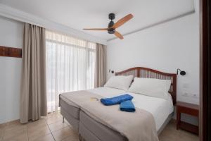 a bedroom with a bed with a ceiling fan at Sunsuites Carolina in San Agustin