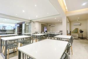 an empty classroom with white tables and chairs at FabHotel Blue Dawn Gachibowli in Gachibowli