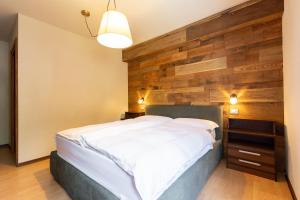 a bedroom with a large bed with a wooden wall at Appartamento Petit Flower in Valdidentro