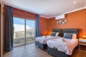 two beds in a room with a large window at Central Malta Gem - 3BR Apartment with Balconies in Mosta