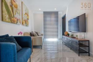 a living room with a blue couch and a tv at Central Malta Gem - 3BR Apartment with Balconies in Mosta
