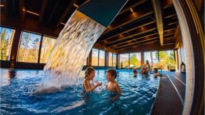 a group of children in a swimming pool with a water fountain at Resort Drevenice Terchova in Terchová