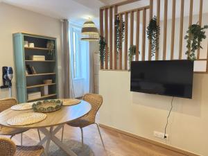 a living room with a table and a flat screen tv at Le Stervin in Villefranche-sur-Saône