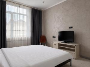 a hotel room with a bed and a television at AiTumar boutique hotel in Almaty