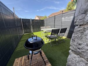 a grill on a patio with a table and chairs at Le Triplex - cosy avec petit jardin in Longueville