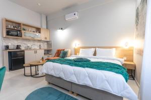 a bedroom with a large bed and a small kitchen at Breeze Apartments Megara - Echo in Megara