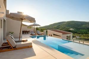 a pool with chairs and an umbrella on a building at Meliora Exclusive Villas Parga in Parga