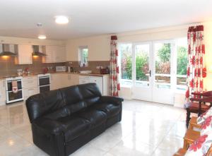 a living room with a black leather couch in a kitchen at Ballyvoy Camping Barn in Willenhall