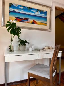 a white desk with a plant and a painting on the wall at Żuławski Dom in Nowy Dwór Gdański