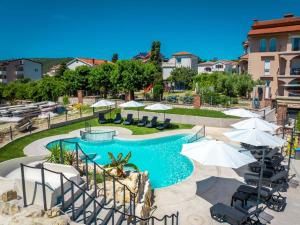 a swimming pool with umbrellas and chairs and a pool at Lopar Family Residence 543a in Lopar