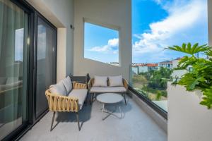 a balcony with two chairs and a table and a window at Calista Horizon by Booking Kottas in Kallithea Halkidikis