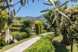 a path through a garden with mountains in the background at Artemis' Garden in Skopelos Town