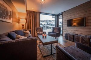 a living room with a couch and chairs and a tv at Skistar Lodge Hemsedal in Hemsedal