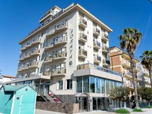a tall white building with palm trees in front of it at Hotel Soraya in San Benedetto del Tronto