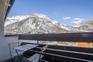 a table and chairs on a balcony with a mountain at Résidence les Cimes - Centre Val d'Isère in Val-d'Isère