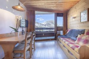 a living room with a couch and a table and a window at Résidence les Cimes - Centre Val d'Isère in Val-d'Isère