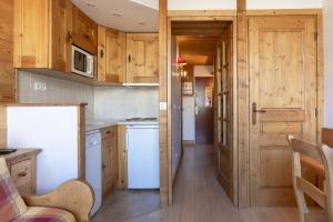 a kitchen with wooden cabinets and a white refrigerator at Résidence les Cimes - Centre Val d'Isère in Val-d'Isère +5 photos