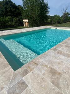 a swimming pool with blue water and a tile floor at Auberge Gardoise in Vallérargues