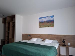 a bedroom with a bed with a green blanket and flowers at Penzión CONTESA in Rožňava +43 photos
