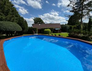 a large blue swimming pool in front of a house at Ostoja Relaksu Cieciorka in Kaliska
