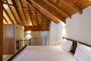 a bed in a room with wooden ceilings at Feel Discovery Casa da Aldeia in Mós