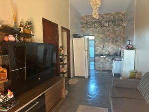 a living room with a large television and a kitchen at Casa do Bento - Lençóis Maranheses in Santo Amaro