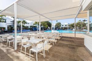 a group of tables and chairs under a tent near a pool at THB Royal in Playa Blanca
