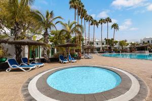 a pool at a resort with chairs and palm trees at THB Royal in Playa Blanca +62 photos