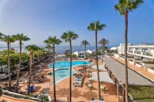 Blick auf den Pool des Resorts mit Palmen in der Unterkunft Hotel THB Flora in Puerto del Carmen