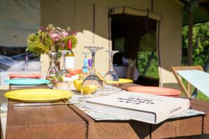 a table with plates and glasses and a book on it at The Firs Glamping in Welland